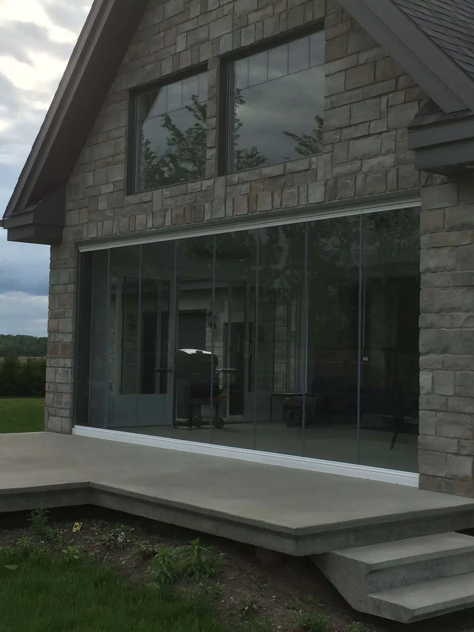 Stone house with full-height glass wall system