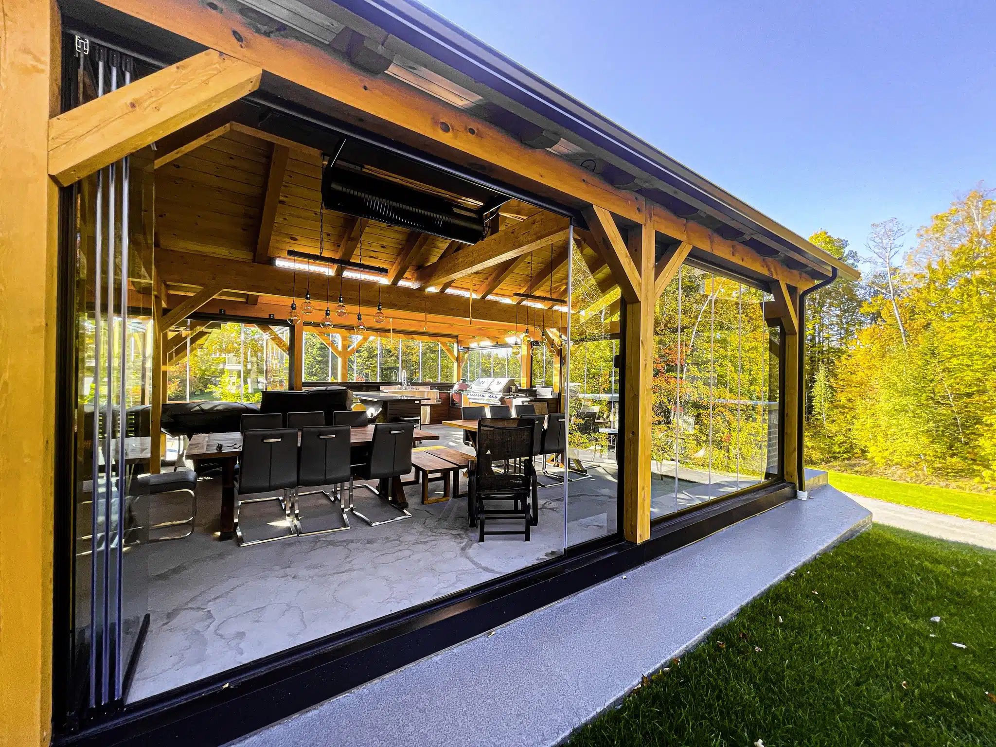 Outdoor dining area under wooden pergola with glass walls