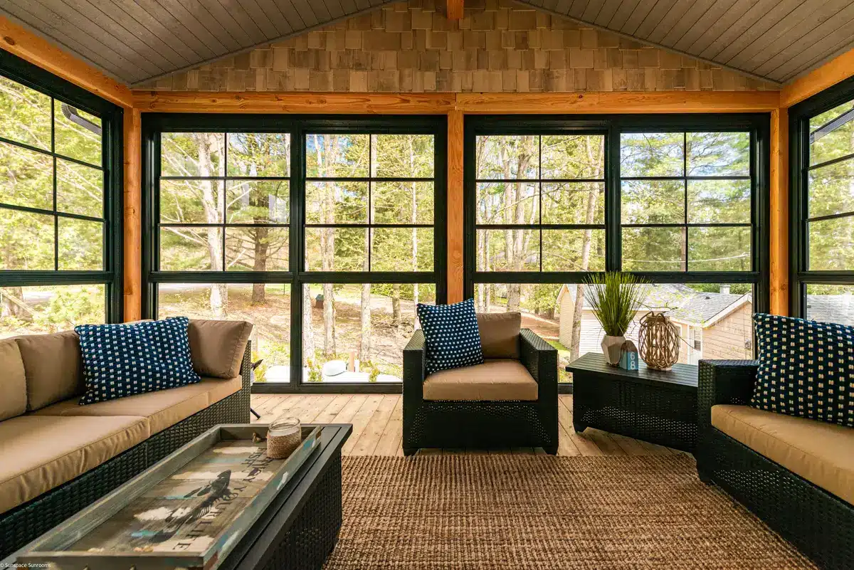Black-framed sunroom with wooden beams and wicker furniture